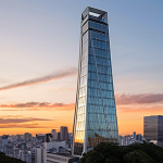 **Prompt:** Modern architecture featuring the Nishiazabu Hills Mori Tower in Tokyo at sunset. Focus on the sleek glass and steel design with a warm, inviting atmosphere. The Mori Art Museum should be visible near the top, showcasing art at a great height.
